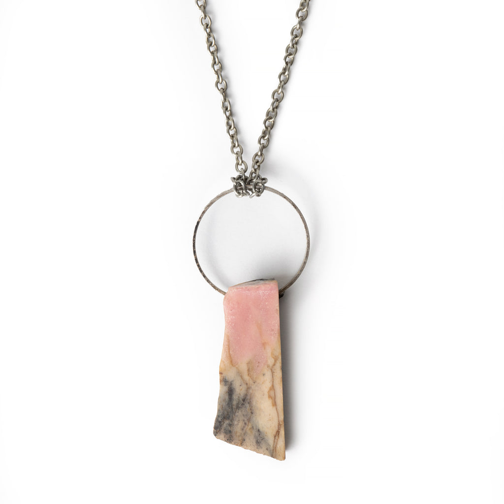 Pink and cream mixed flat gemstone hanging on silver tone hoop, on silver chain. Necklace is on solid white background.