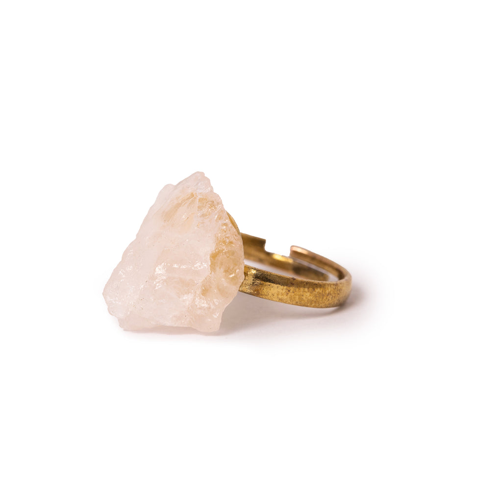 3/4 view of rough cut rose quartz ring laying on solid white background.