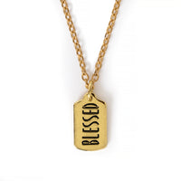 Gold colored charm with "Blessed" engraved, on gold chain. Image has solid white background.