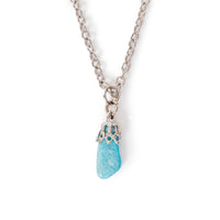 A small tumbled turquoise stone in silver bail on chain, sitting on solid white background.