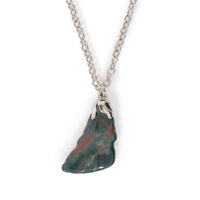 A medium sized tumbled bloodstone in silver bail on chain, sitting on solid white background.