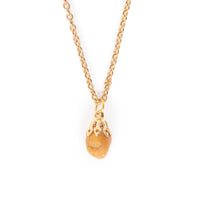 A smooth goldish tone stone, hanging on gold bail and chain. Image has a solid white background.