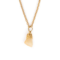 A light cream tone stone hanging on gold bail and chain. Image has a solid white background.