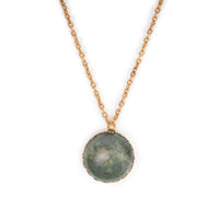 Green gemstone cab in gold backing, hanging on gold chain.