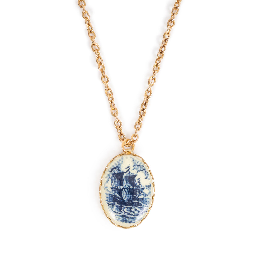 Vintage blue and cream cab, on gold backing, hanging on gold chain. Image is on a solid white background.
