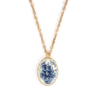 Vintage blue and cream cab, on gold backing, hanging on gold chain. Image is on a solid white background.