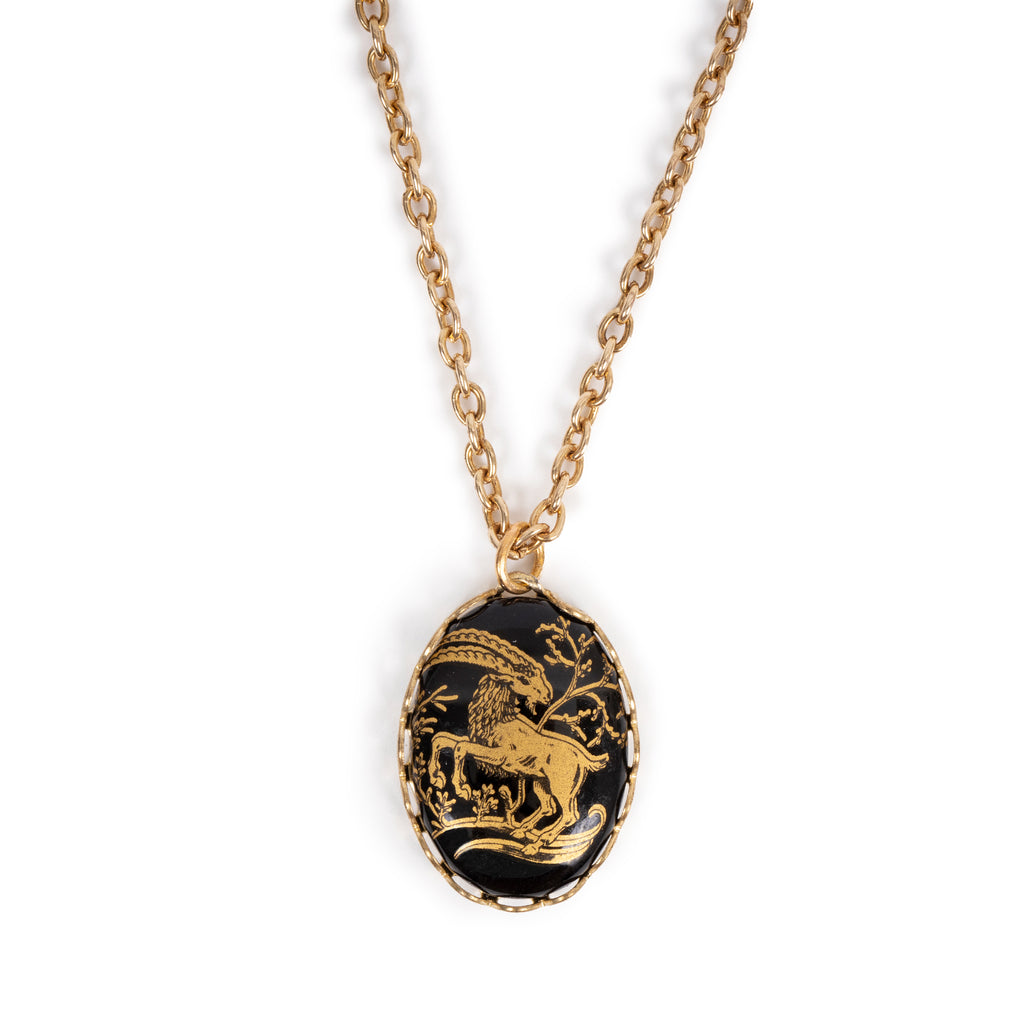 Golden ram cab on gold backing, and hanging on gold chain. Solid white background. 