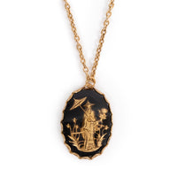 A golden traditional Japanese figure in a garden, on black back. Cab is on gold backing, hanging on gold chain. Solid white background.