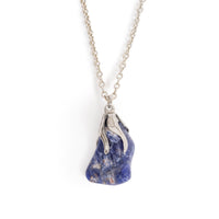 Smooth Sodalite on silver glue on bail, hanging on silver chain. Image has solid white background.