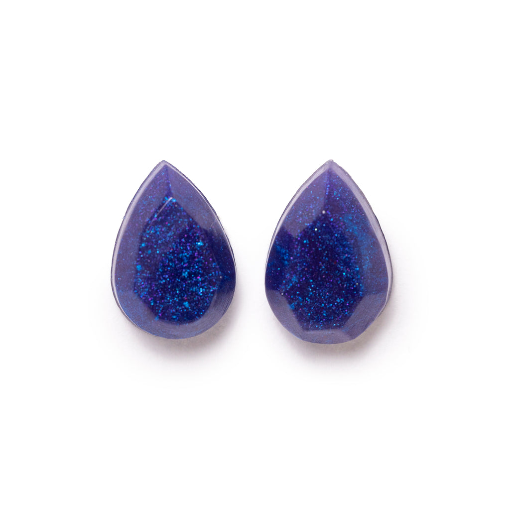 Blue glittery teardrop shaped earrings both facing forward. Image is on a solid white background.
