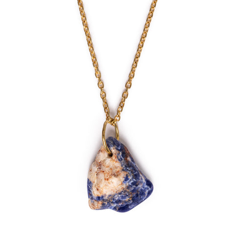 Blue and white/pink sodalite pendant hanging on gold tone chain. Image has a solid white background. 