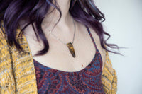 Close of up tiger's eye necklace on female model's neckline. on silver chain