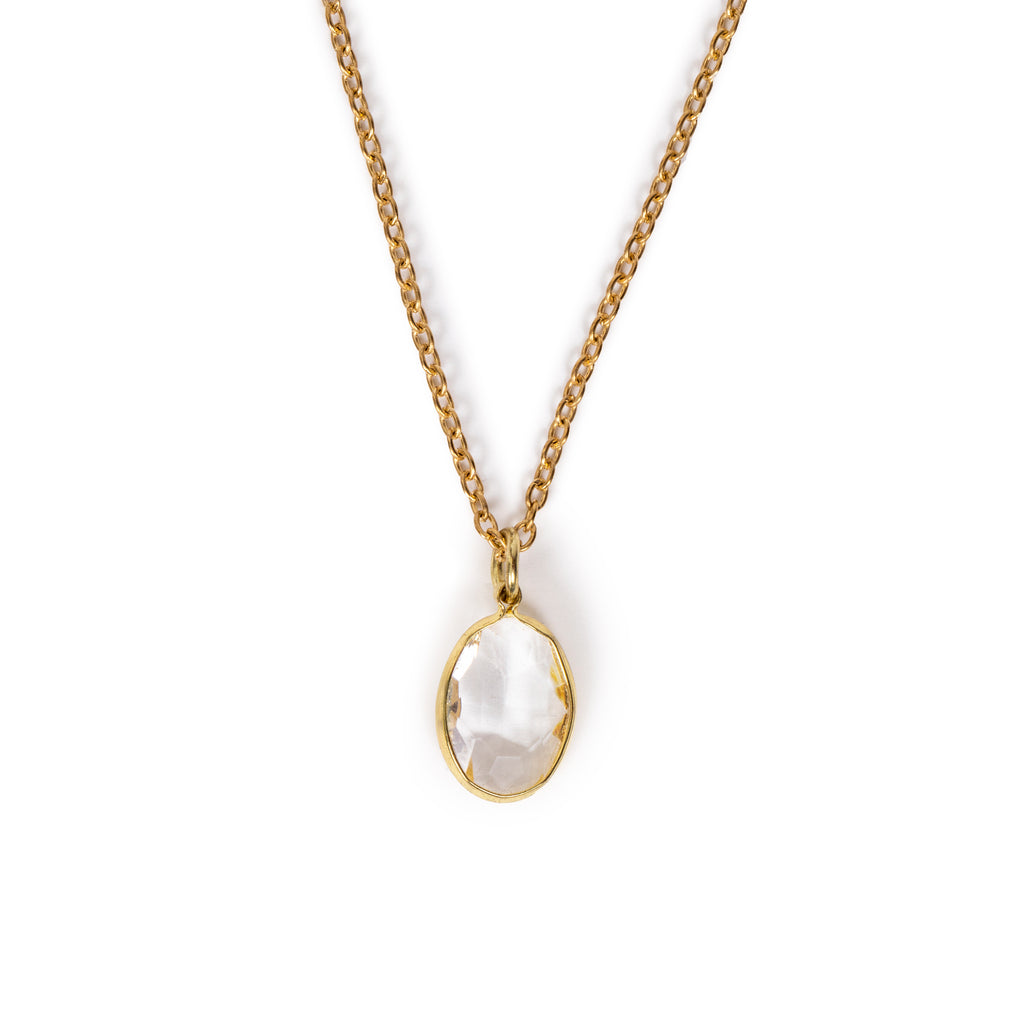Clear faceted glass charm hanging on gold chain, on solid white background.