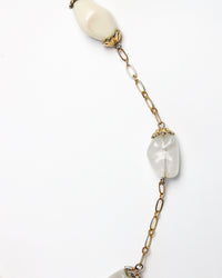 Close up detail of beaded gold strung necklace, laying on solid white background. 