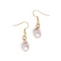 Overhead view of pearl drop gold earrings on solid white background.